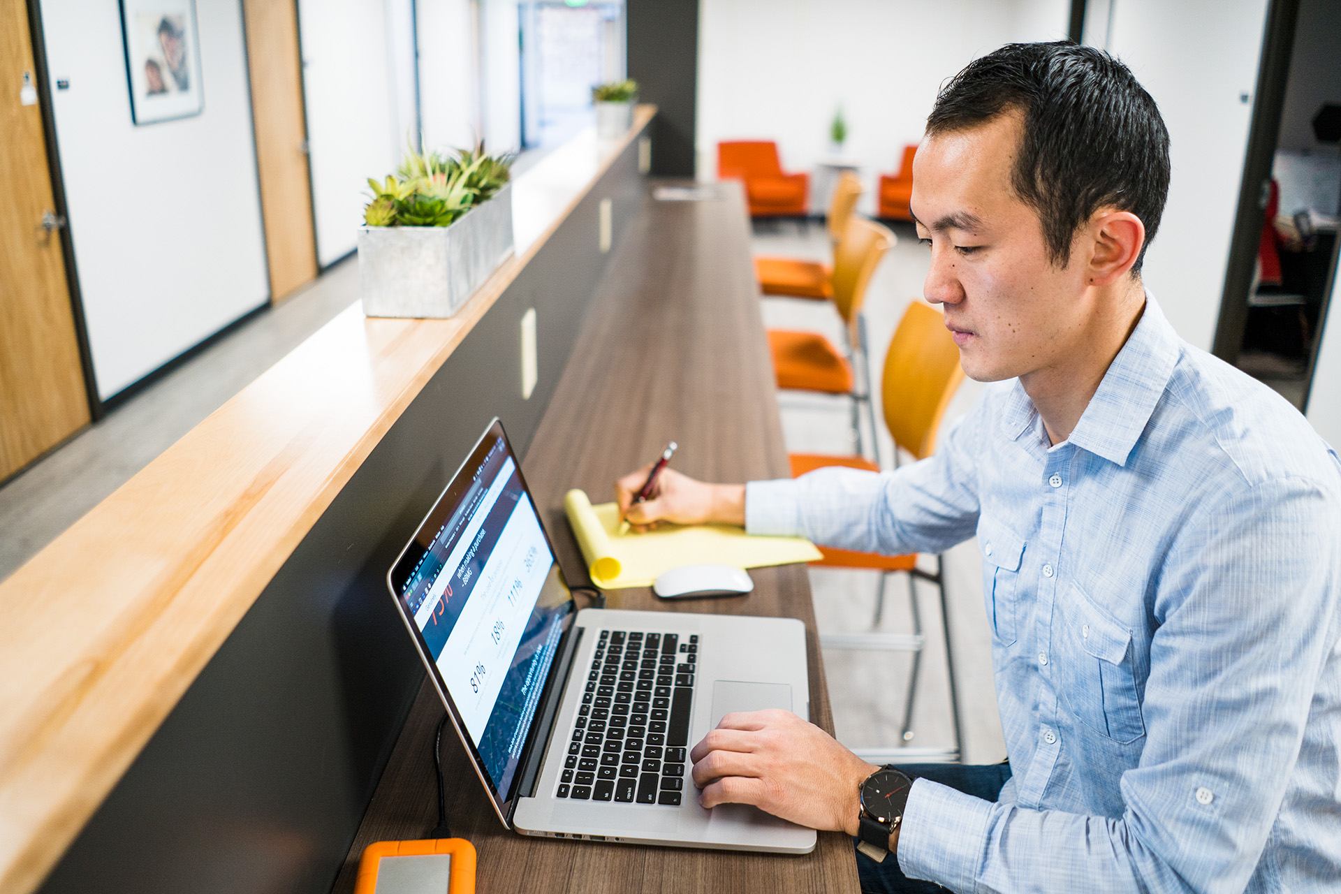 Man working at a desk with a laptop and a notepad.