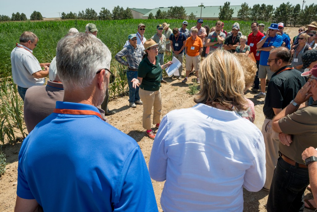 A group of people gathering outdoors at an agricultural research station