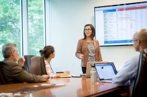 Woman speaking to coworkers during a meeting at a table.