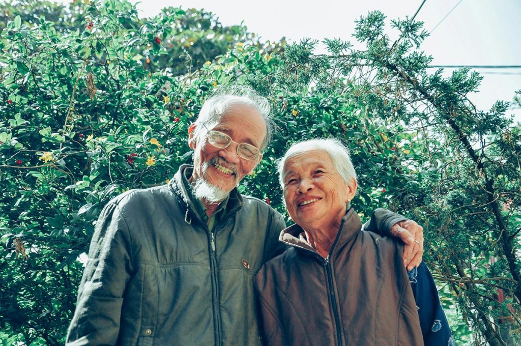 A senior couple outside smiles happily.