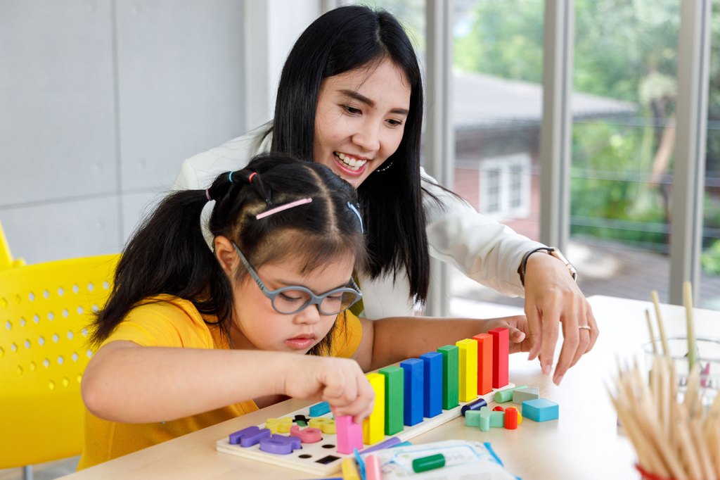 A young girl and a woman playing with colorful educational toys at a table.