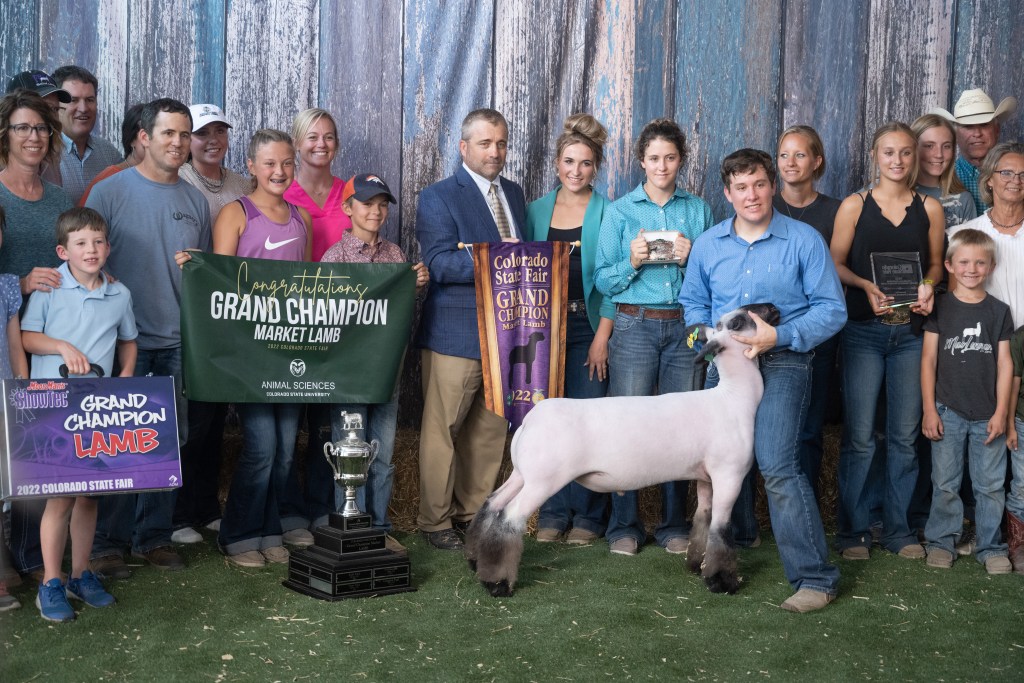 A group of people and a goat posing at he 2022 Colorado State Fair.