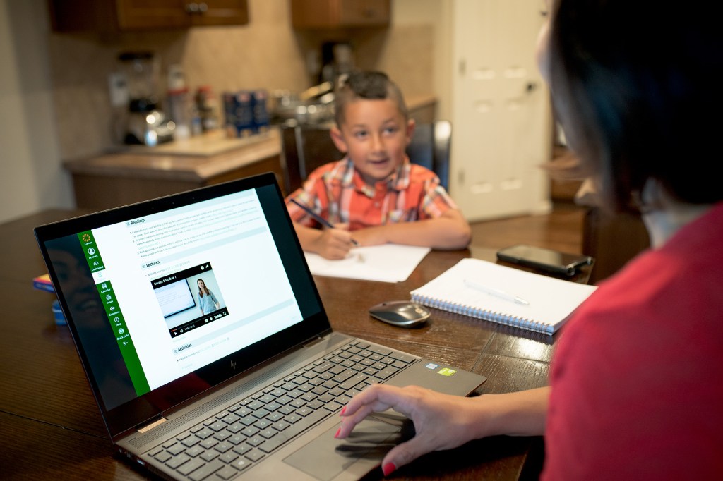 A mom studies at her dining room table while her son does homework.