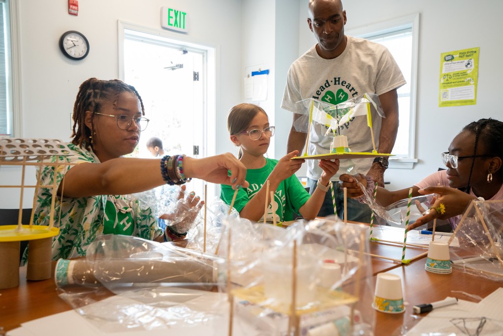 A group of students working on a STEM project, constructing models with various materials in a classroom.