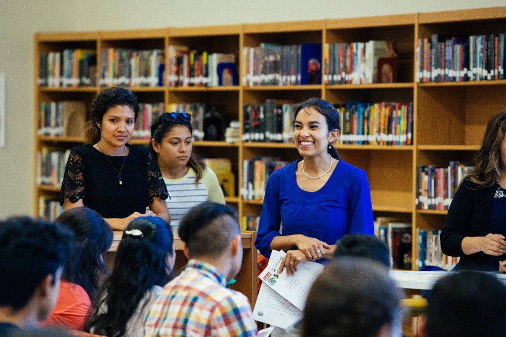 A group of people gather together in a library.