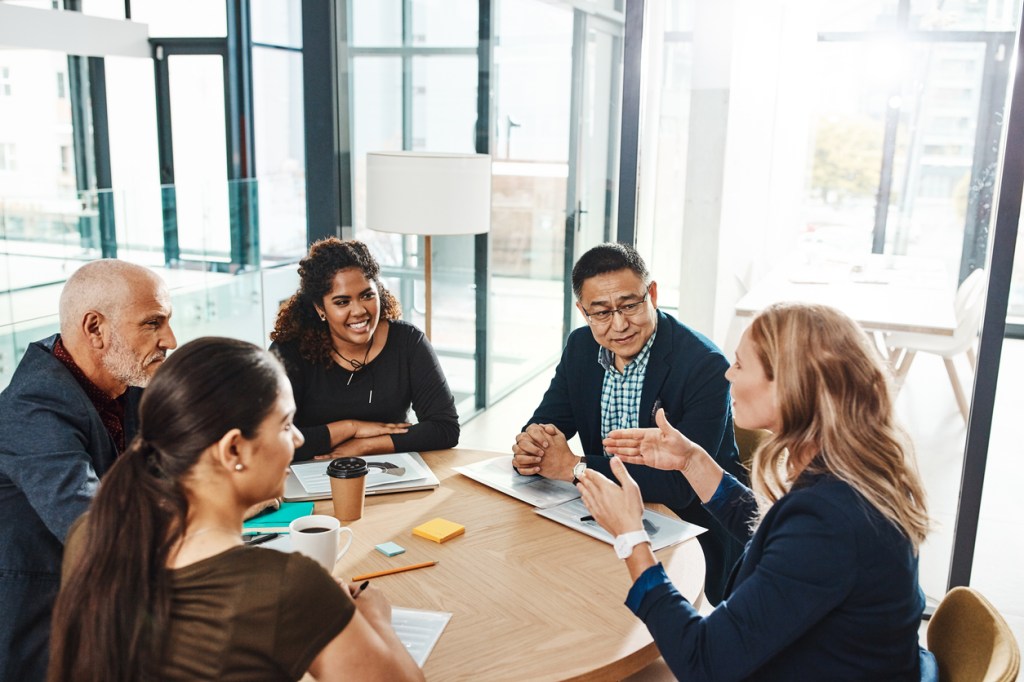 A group of professionals sitting around a conference table, engaged in discussion during a business meeting.