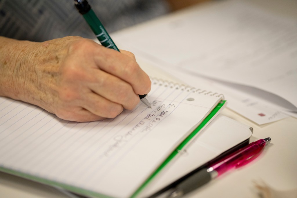 A person writes in a notebook with a pen.