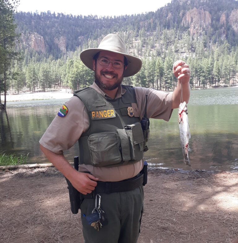 CSU Online student, Aaron Cobas, stands in his ark ranger uniformed CSU Online student shows off the trout he caught.