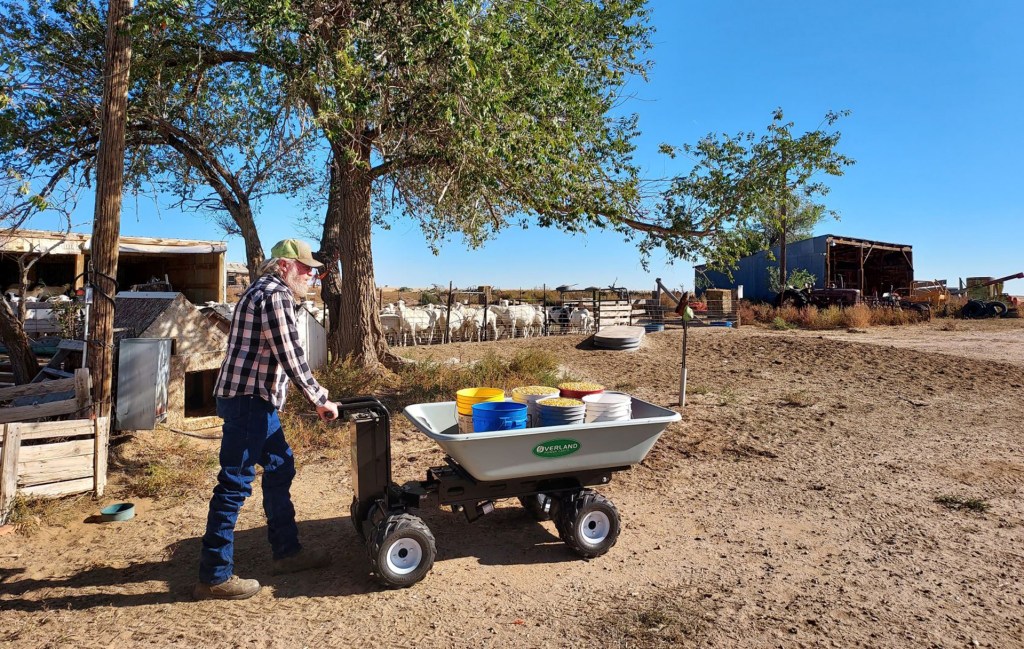 A farmer pushes a wagon full of buckets