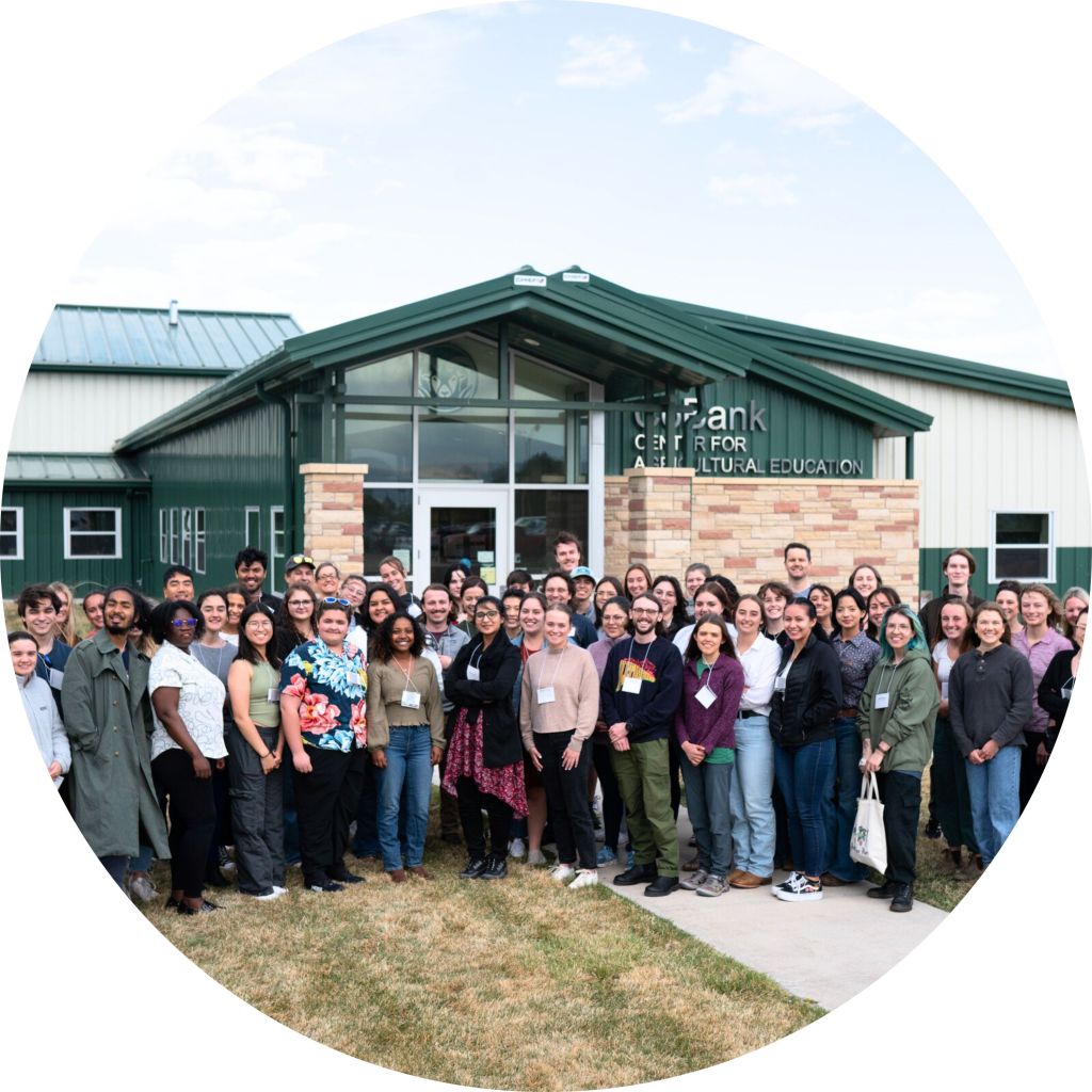 A large group of diverse individuals standing together outside the Lyda Hill Center for Agricultural Education building, smiling and posing for a group photo.