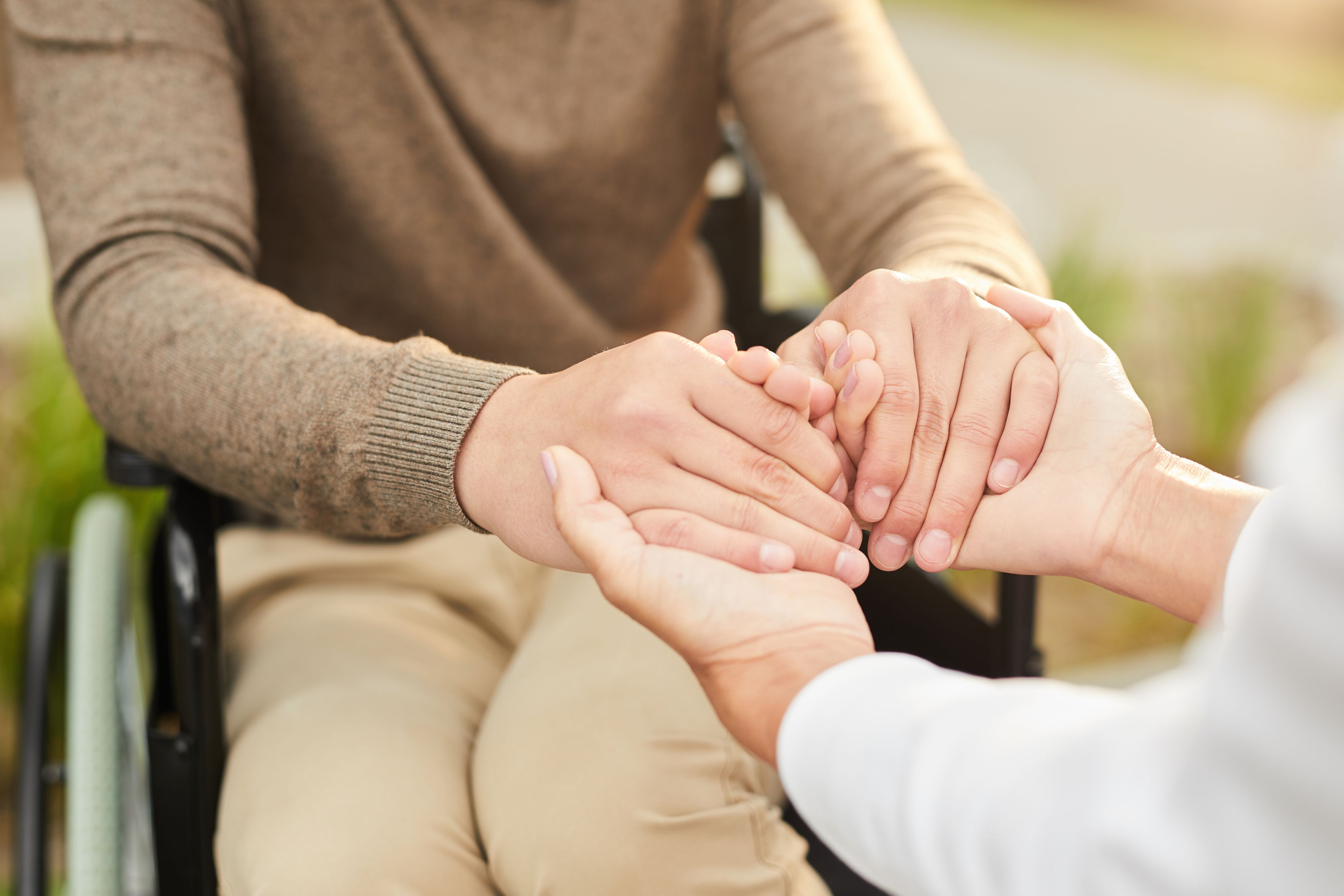 A close-up of hands holding each other in support, representing empathy, care, and the essence of social work and community service.