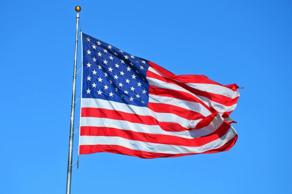 The United States flag breezing in the wind on a flag pole.