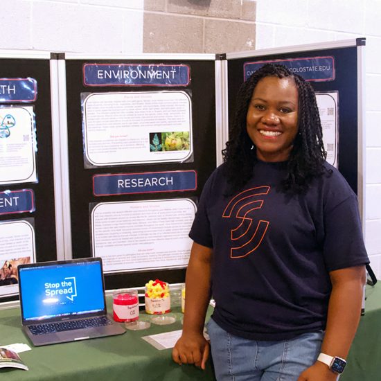 Joy Enyinnaya stands with her Extension internship display presentation boards.